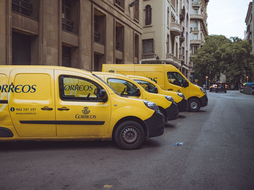 Three yellow delivery vans parked on a street in Barcelona, Spain, showcasing urban logistics.