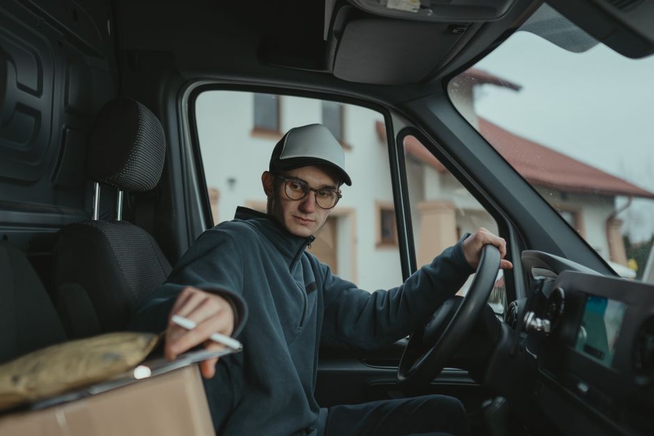Young delivery driver inside a van preparing to deliver a package, showcasing logistics work.
